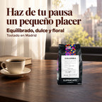 Café de Colombia Supracafé junto a una taza y un libro. Texto: Haz de tu pausa un pequeño placer. Equilibrado, dulce y floral. Tostado en Madrid.